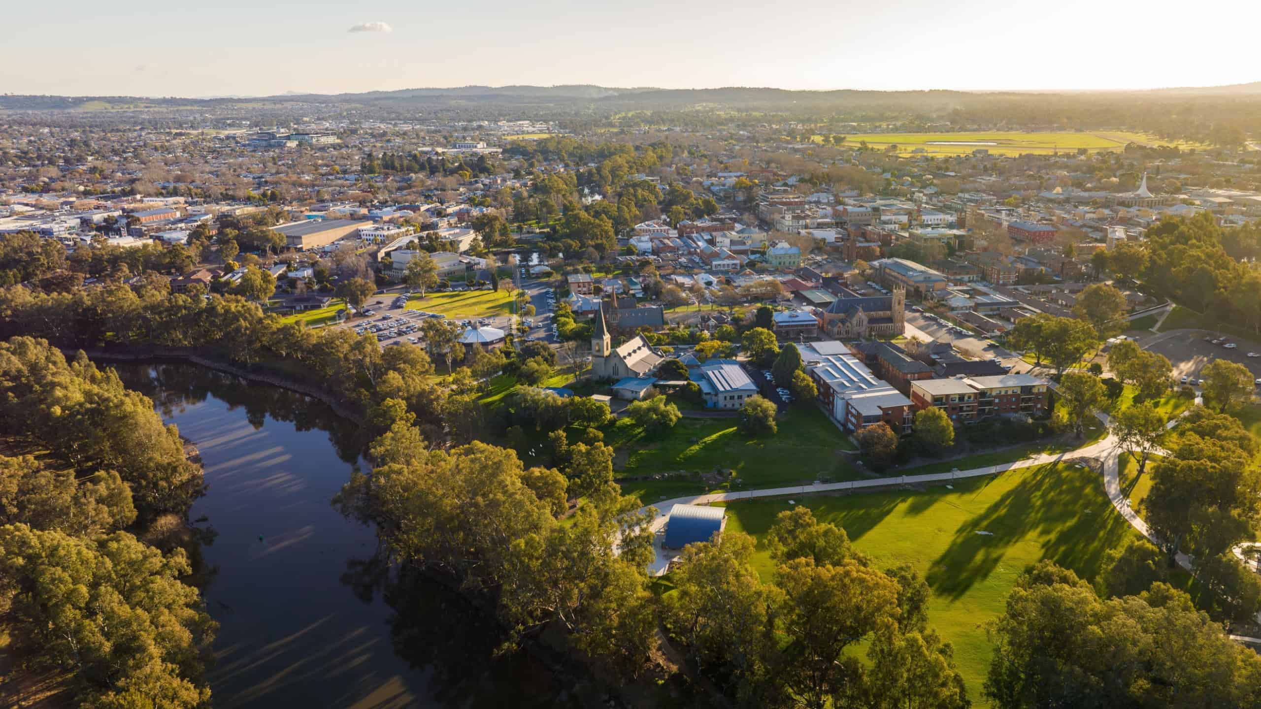 Aerial view of Wagga Wagga, Australia, featuring a lake surrounded by lush greenery and the cityscape in the background