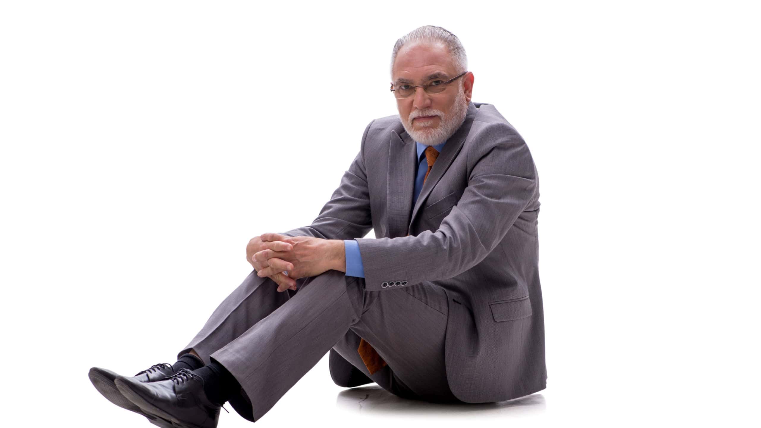Old businessman sitting on the floor isolated on white