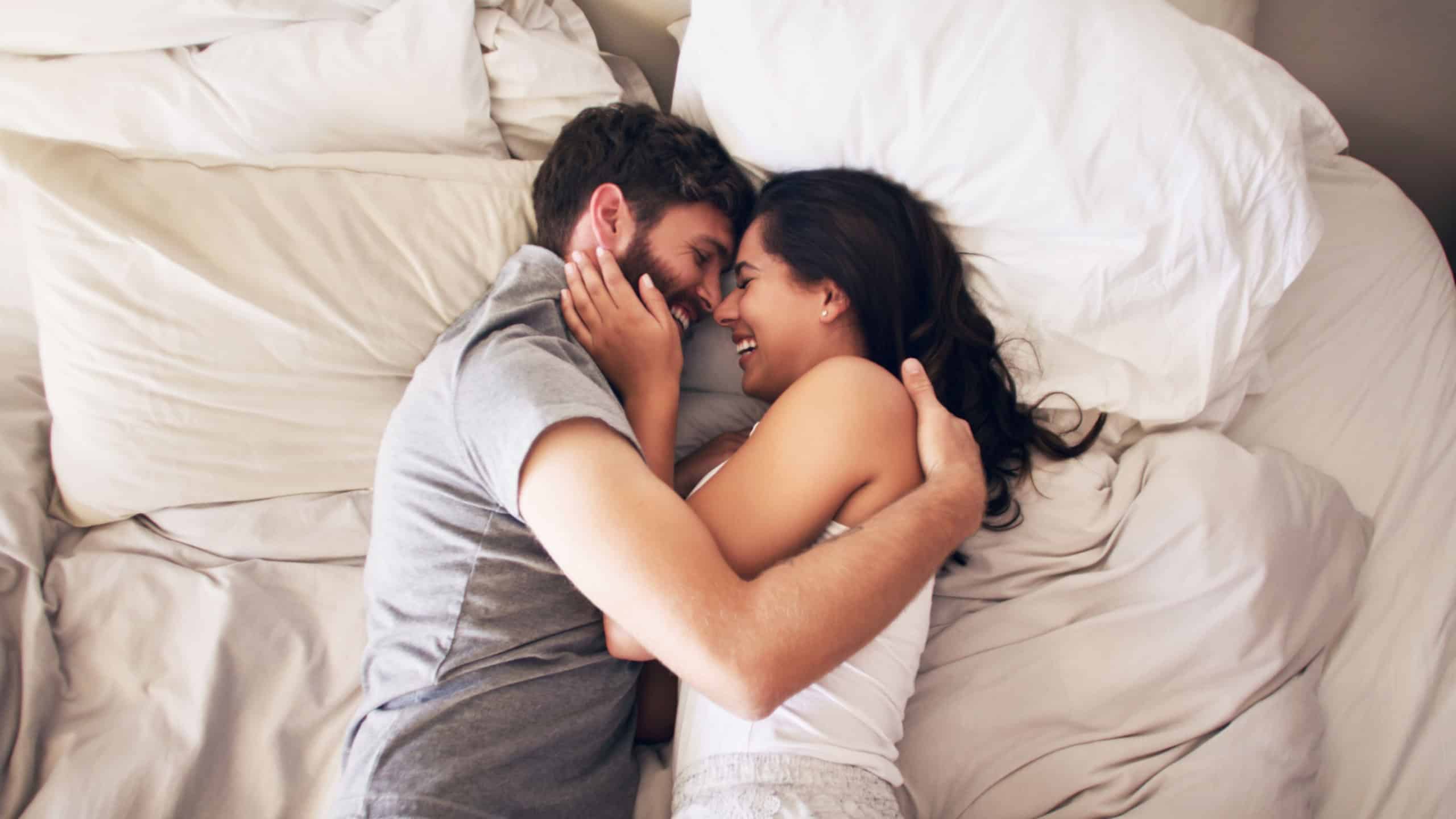 Happy, bed and couple hug at morning with embrace at home with love, marriage and cuddle together. Smile, above and blanket fort in a bedroom in a house with care and romance with cotton duvet