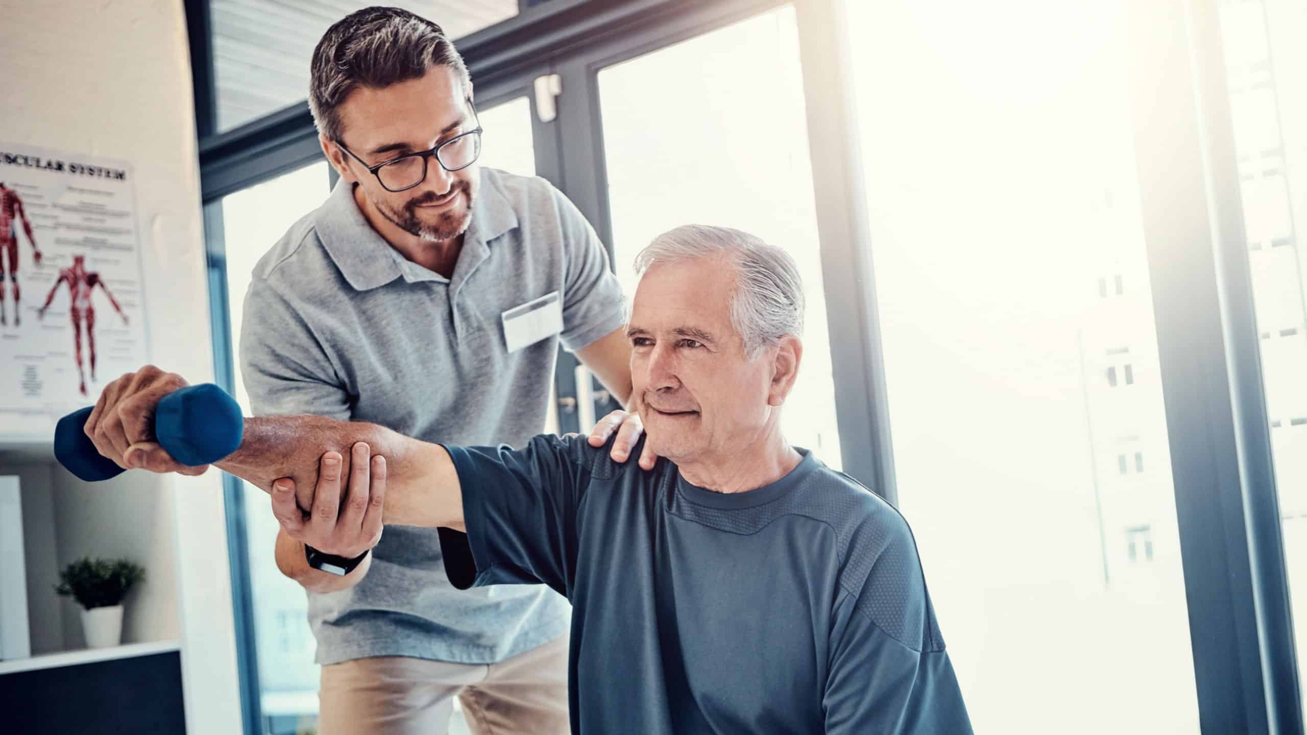 Senior man, physiotherapist and dumbbell with help for progress, recovery and balance for wellness. People, healthcare and rehabilitation from injury with support, care and strong muscle at clinic