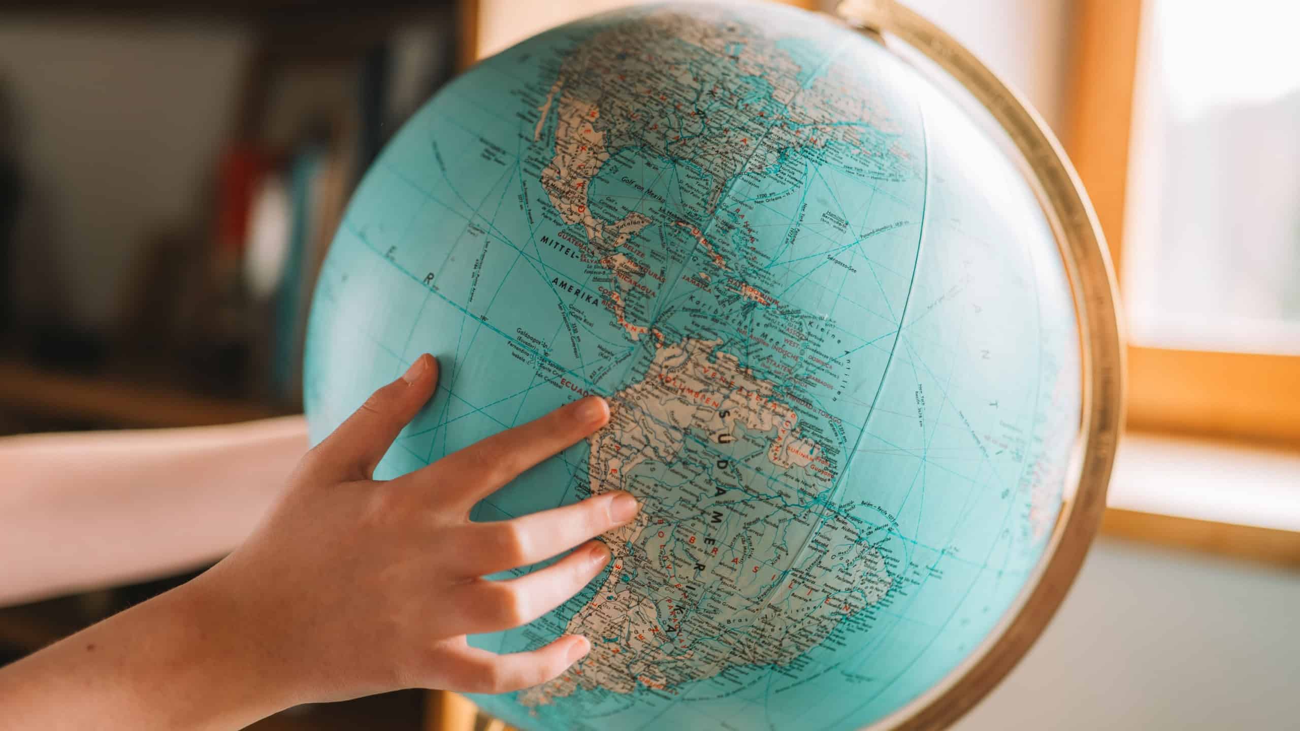 Learn Geography.Trip and travel planning.Globe and hands close-up.childs hands twist the globe and look for countries.Countries, cities and continents on the globe