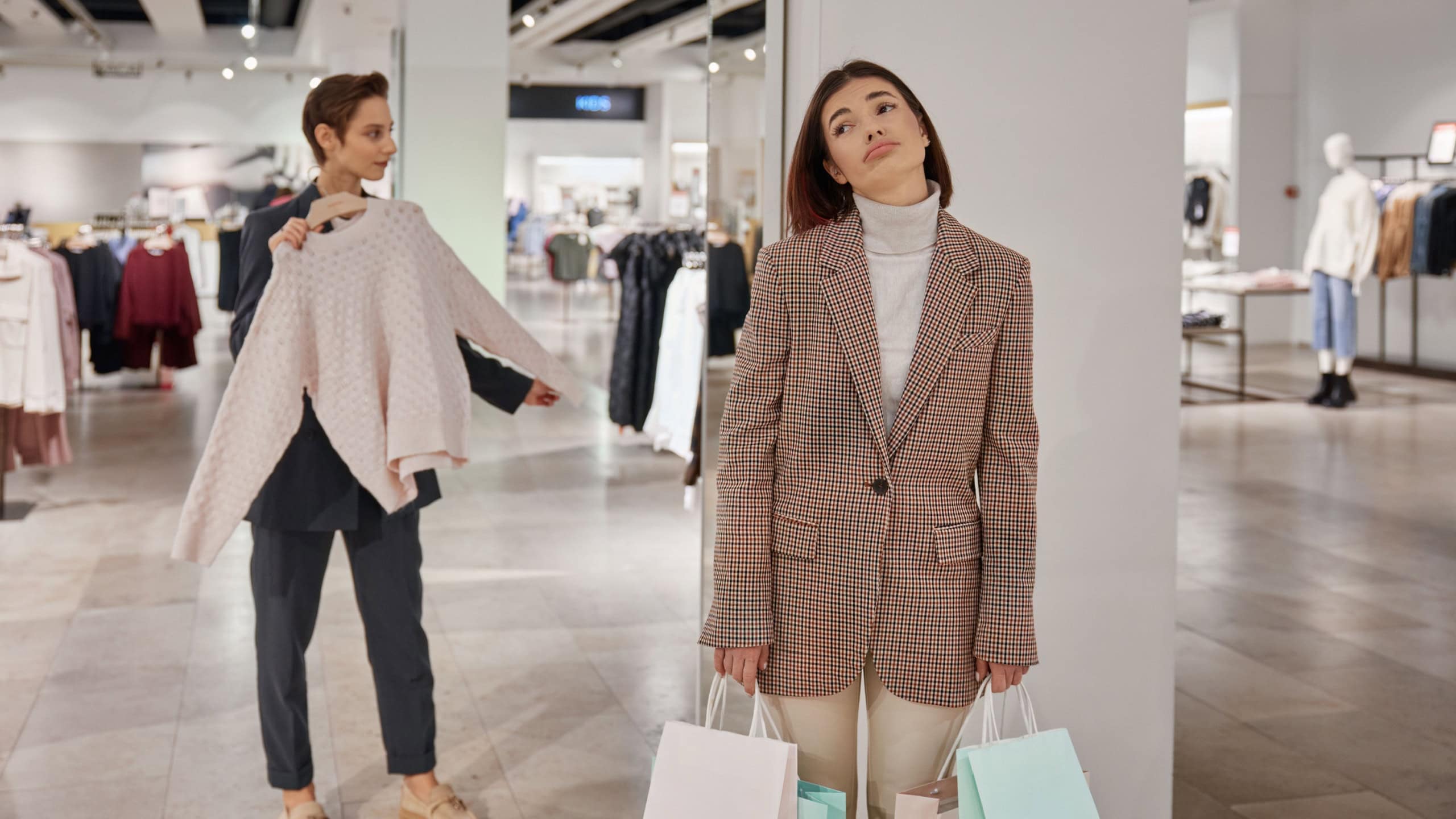 Young tired woman waiting for friend while shopping in clothes store
