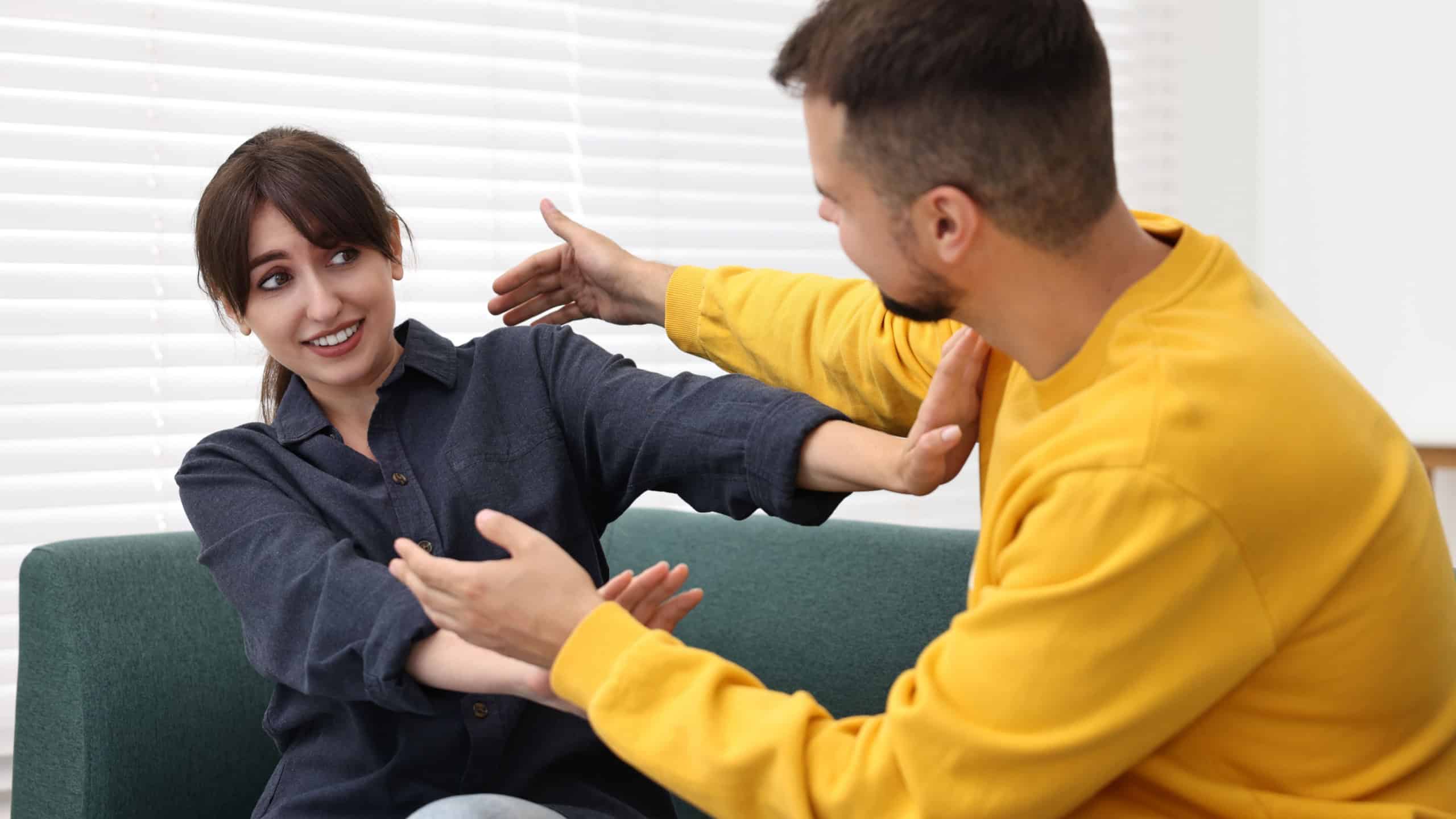 Embarrassed woman refusing from man's hugs at home