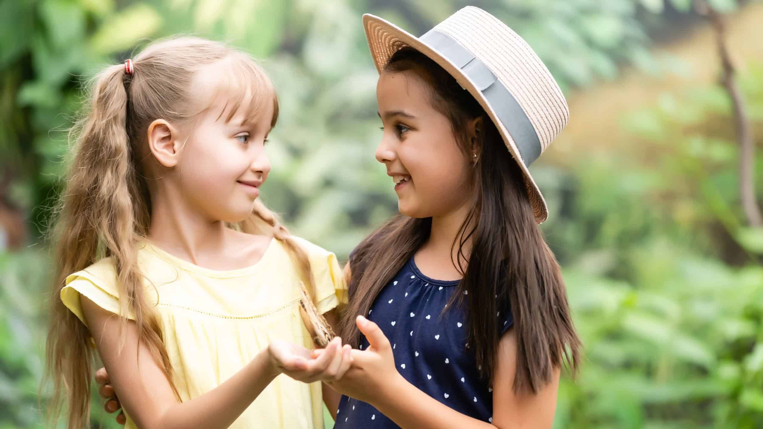 Two little girls with butterflies in a greenhouse