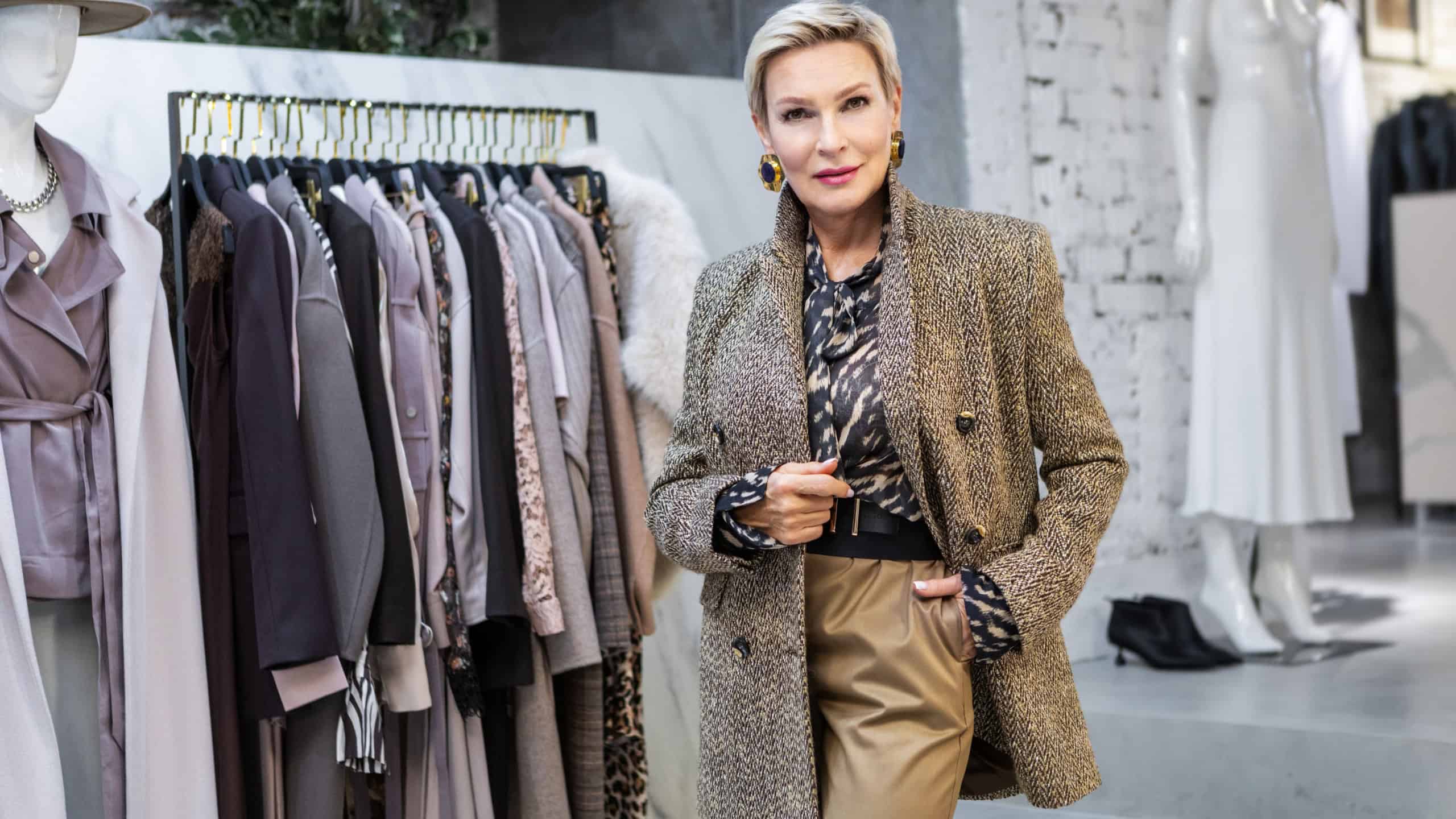Stylish Mature Woman with Short Hair in Fashionable Clothing Standing in female Clothing Store, Owner of Boutique Business. Portrait of Female Entrepreneur