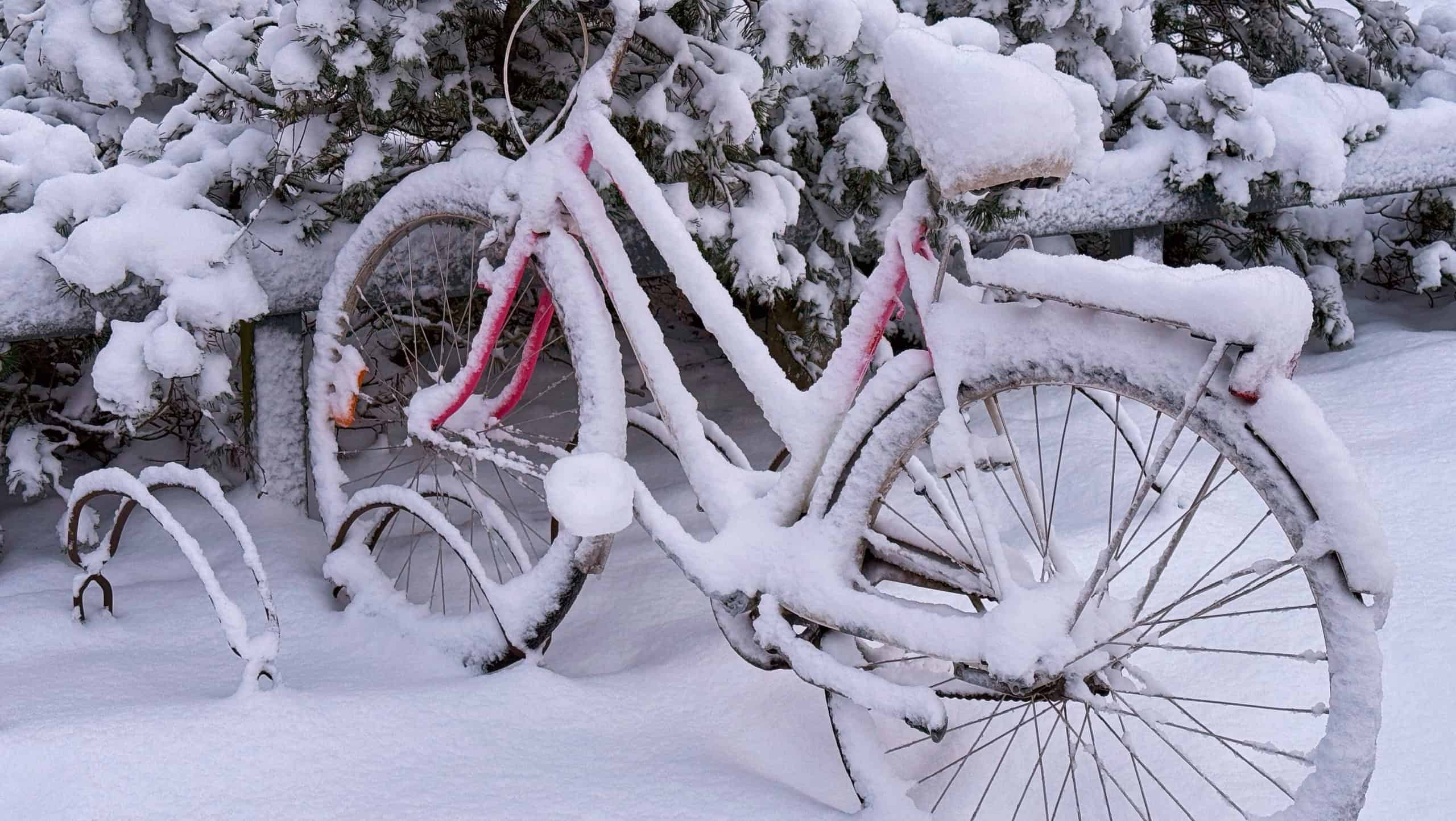 A lonely bicycle under soft snow in a bicycle parking lot.