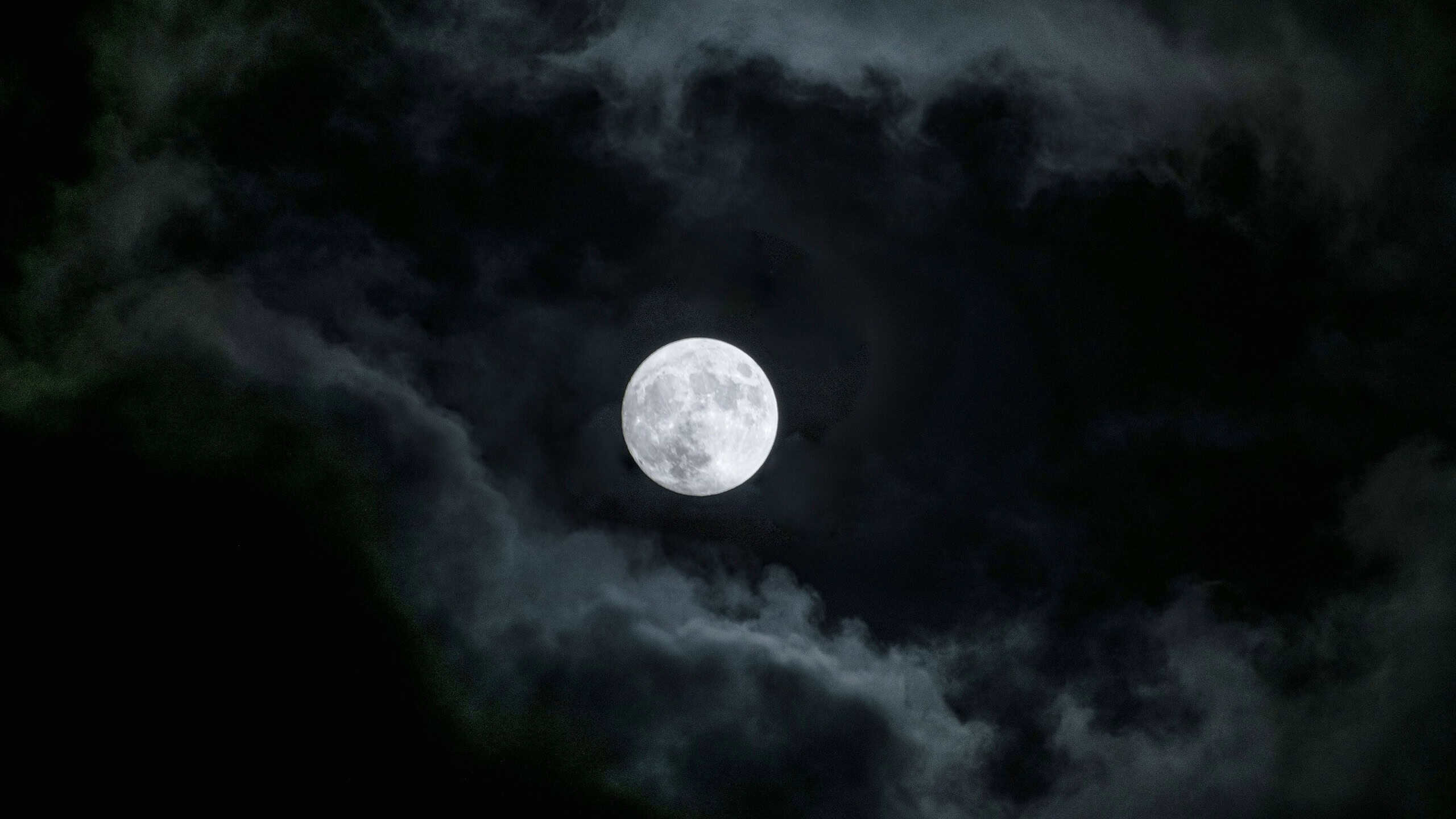 A mesmerizing view of a moon in the dark cloudy sky