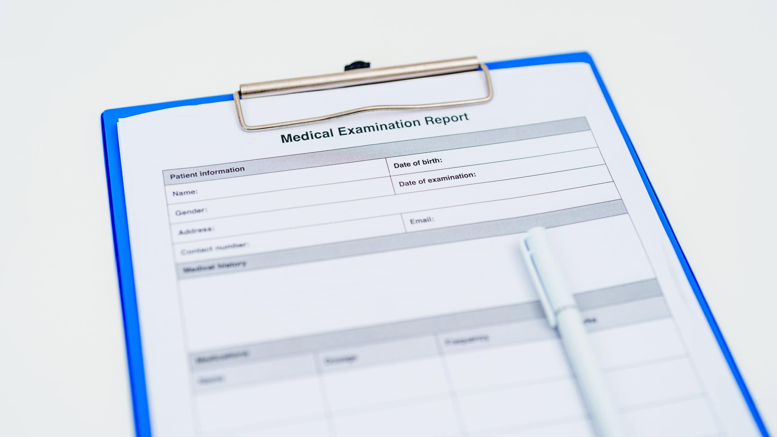 medical examination report form on blue clipboard with white pen of doctor. healthcare documentation, medical records, medical consulting, health checkup and examination concepts