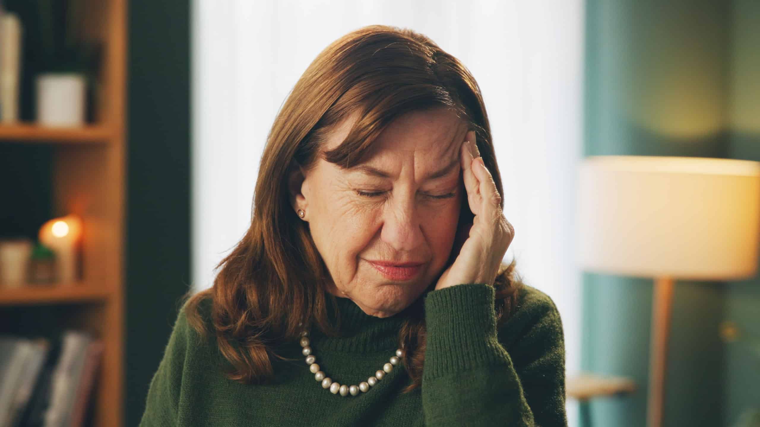 Senior, woman or pain from headache in home with stress, frustrated or confused from brain fog in retirement. Elderly, person and face or migraine with tension, pressure or mental health with anxiety