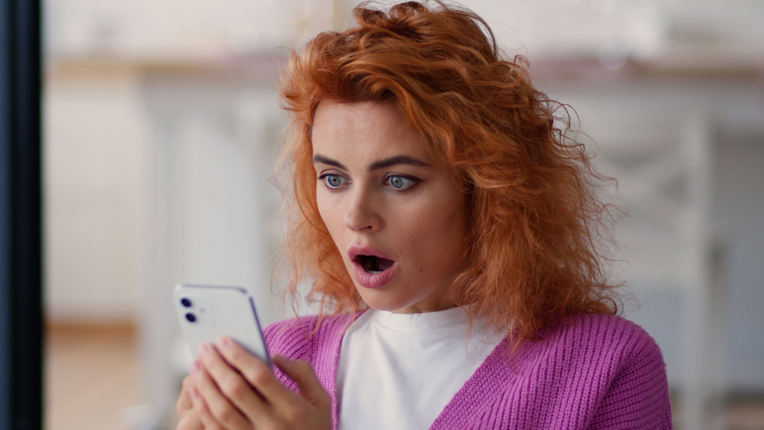 Caucasian woman lady user female girl at home couch indoor looking at mobile phone smartphone bad news shock amazed stunned negative confused online internet cellphone notification big eyes open mouth