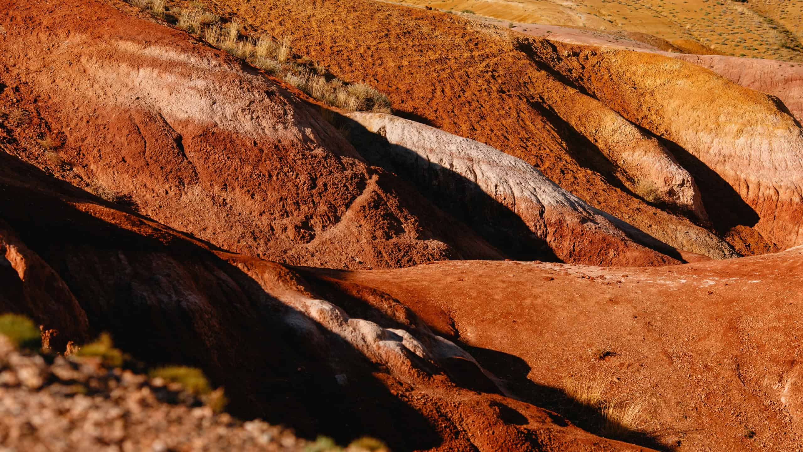 Vibrant multicolored hills at sunset with textured layers and unique geological formations.