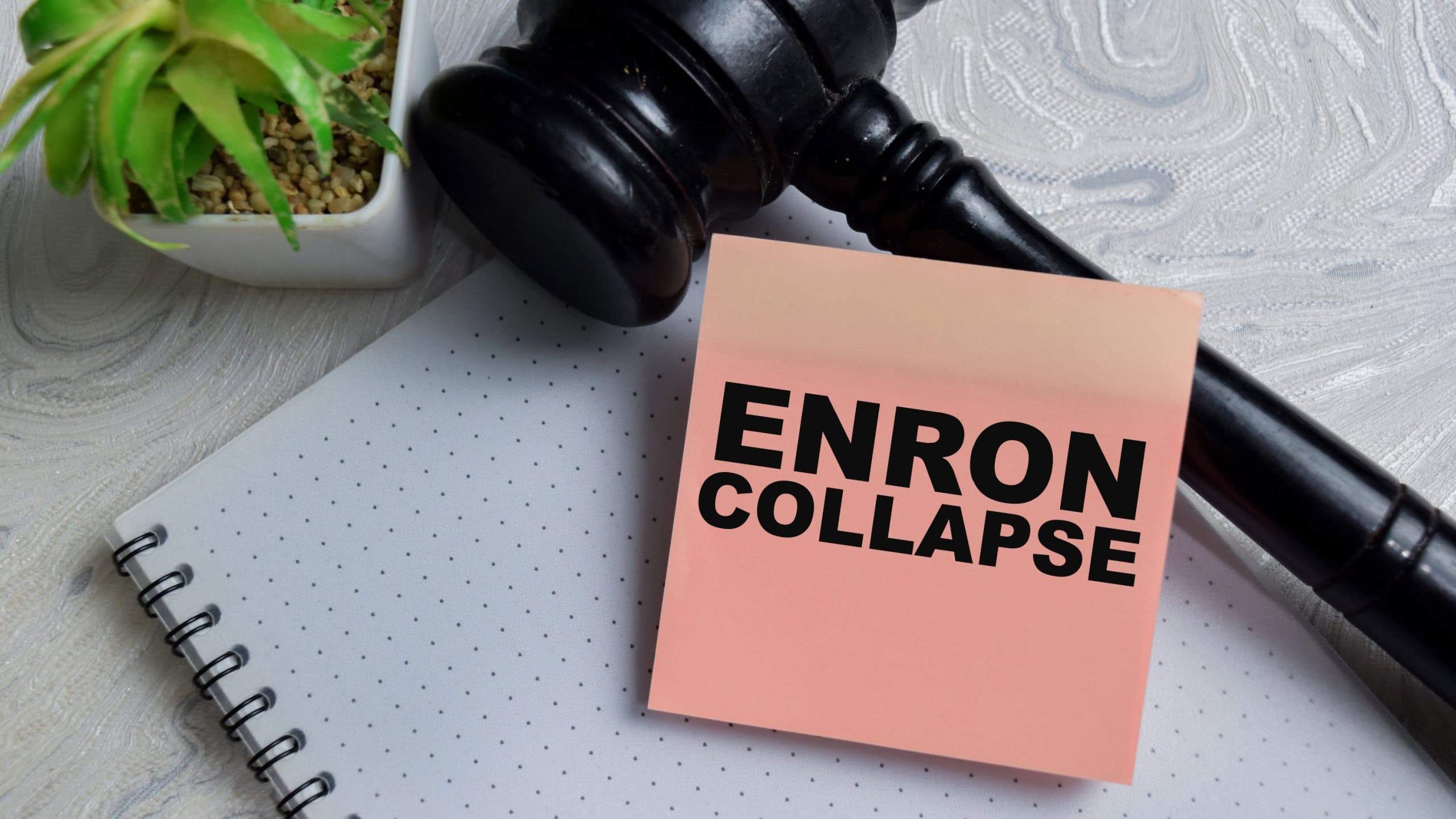 Concept of Enron collapse write on sticky notes isolated on Wooden Table. Representing corporate fraud, financial scandal and legal accountability