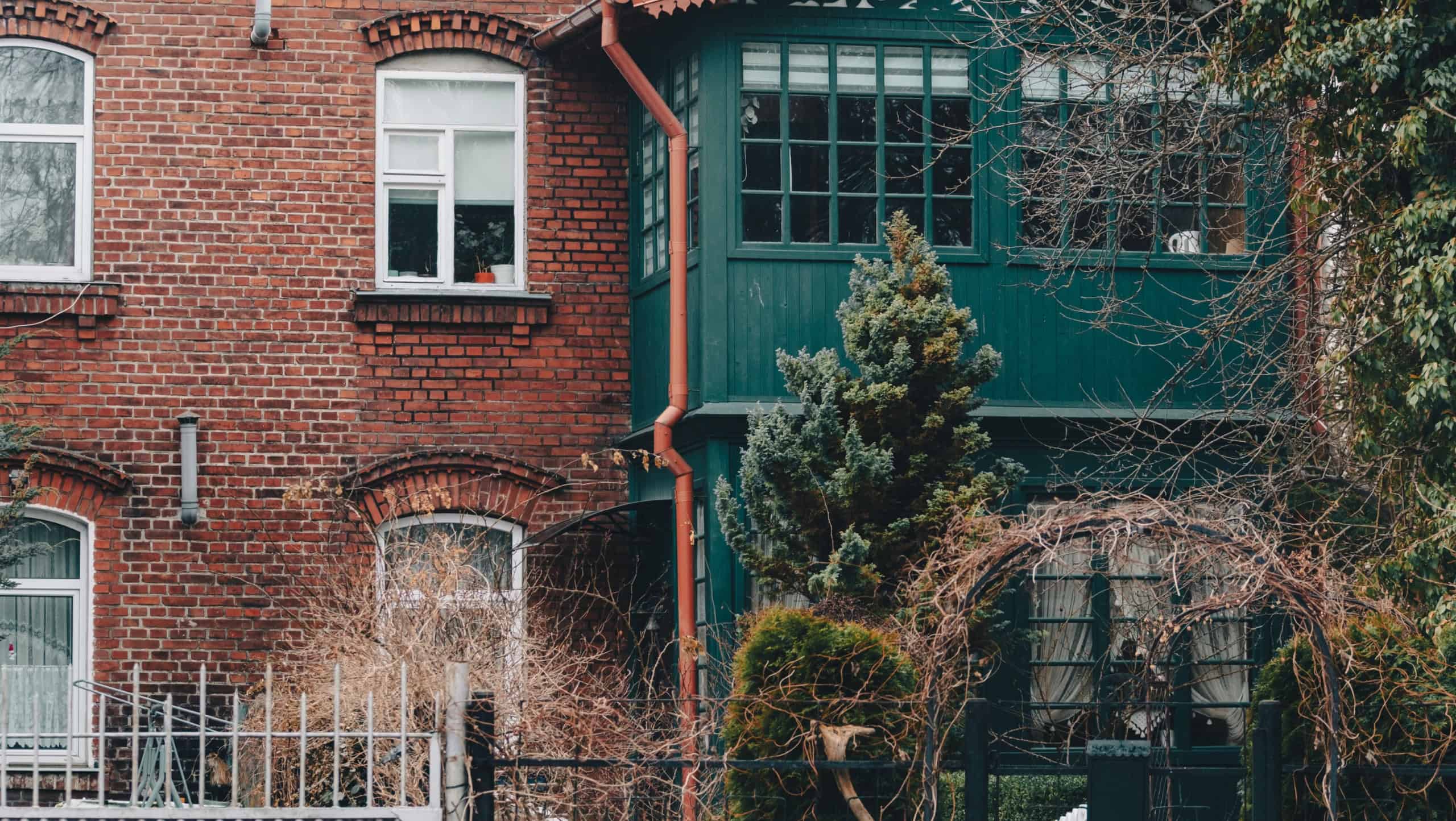 Old brick house facade with green annex building. Vintage architecture and urban living concept. Exterior view of residential property