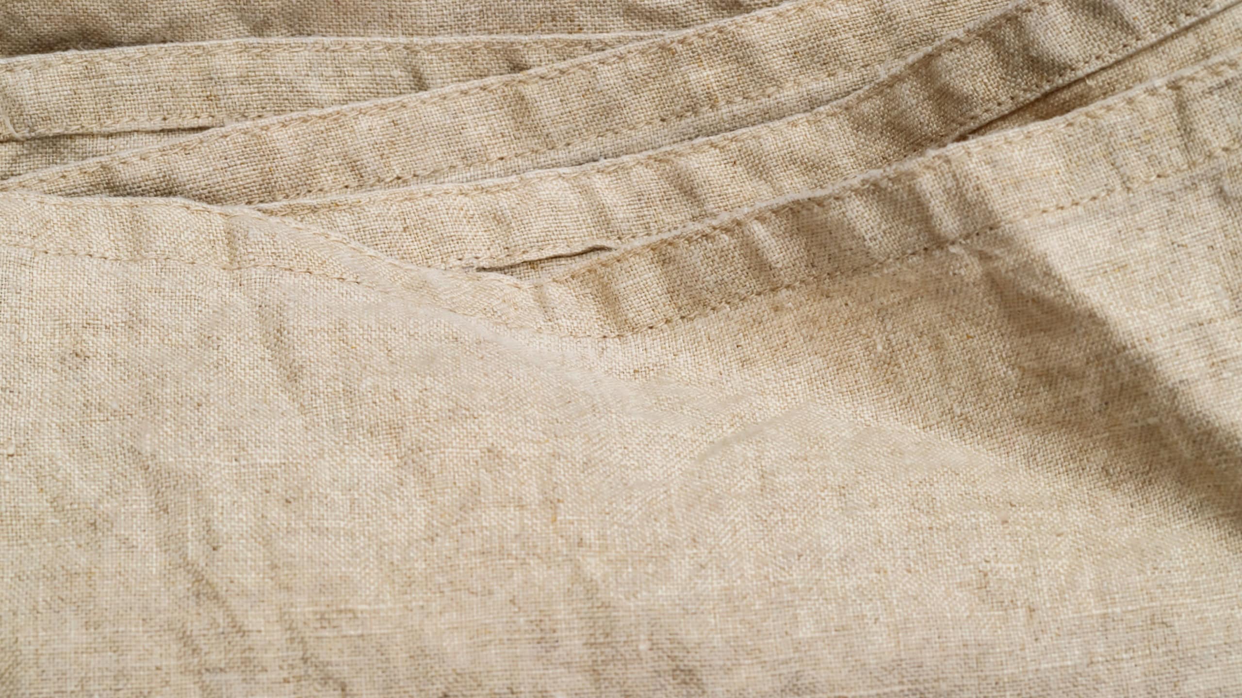 Linen pieces are arranged on a surface, ready for sewing and crafting. The light beige fabric displays texture and pattern.