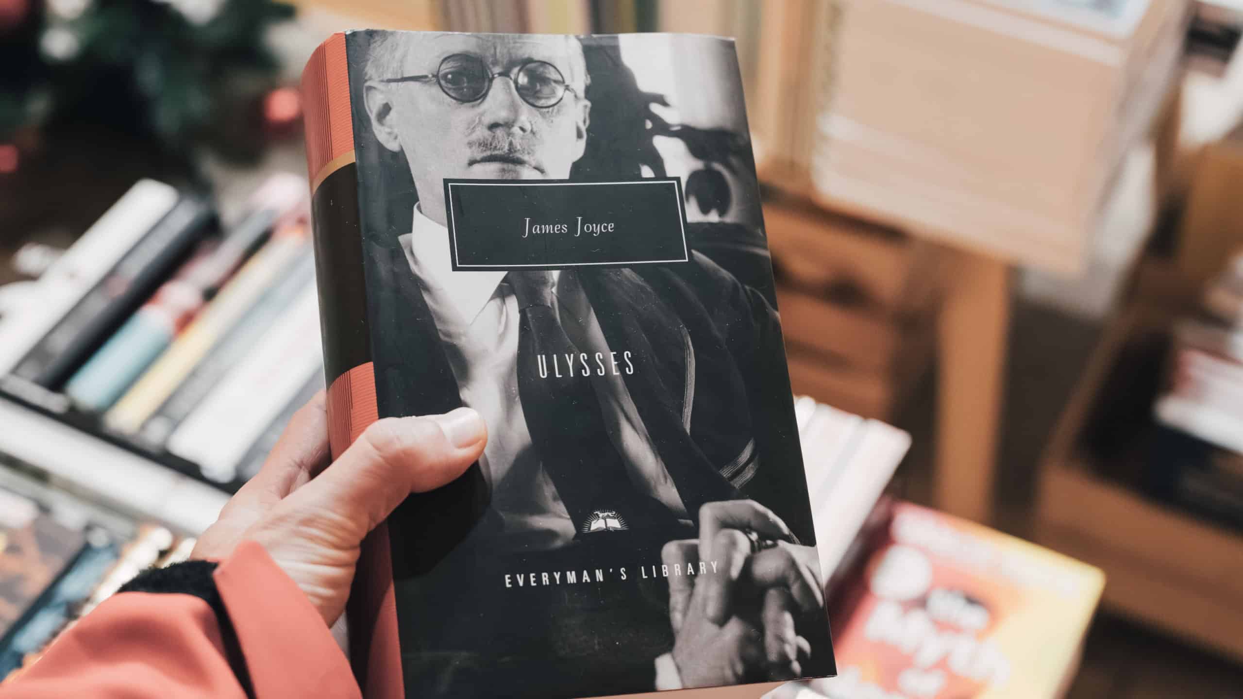 Hand holding a paperback copy of James Joyce's Ulysses from Everyman's Library, browsing literature in a bookshop