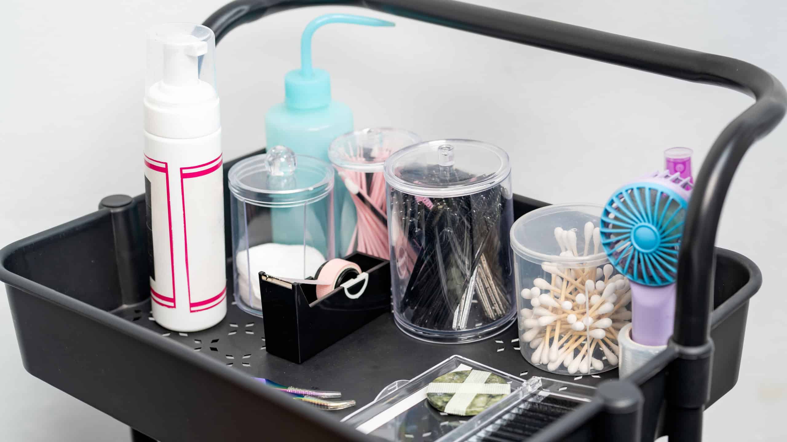 Professional equipment on a rolling utility cart, with various items for lash extensions and beauty treatments in a salon setting