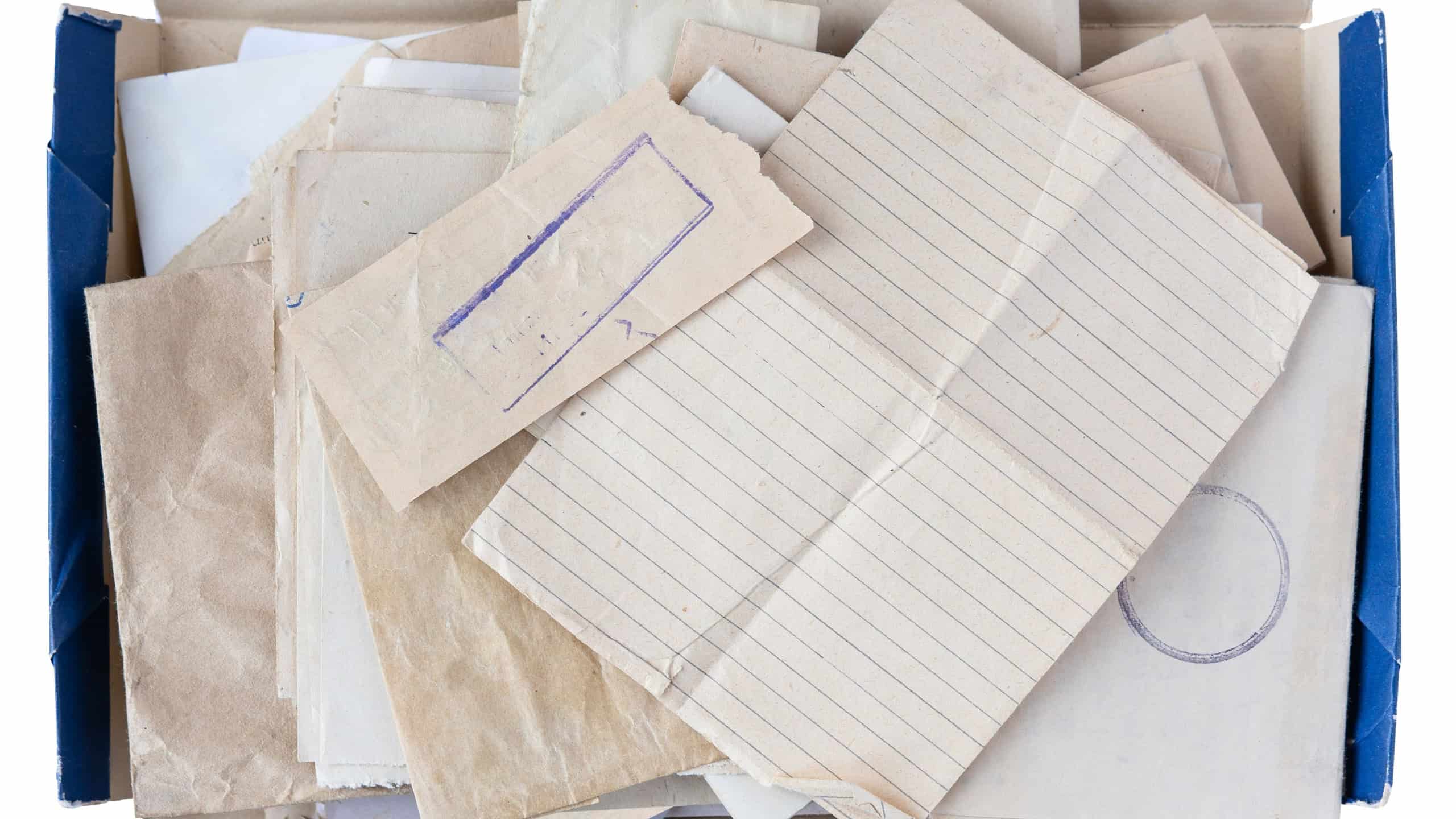 Old handwritten letters and blank lined paper in a blue cardboard box top view isolated on white, concept for archive memory and personal correspondence