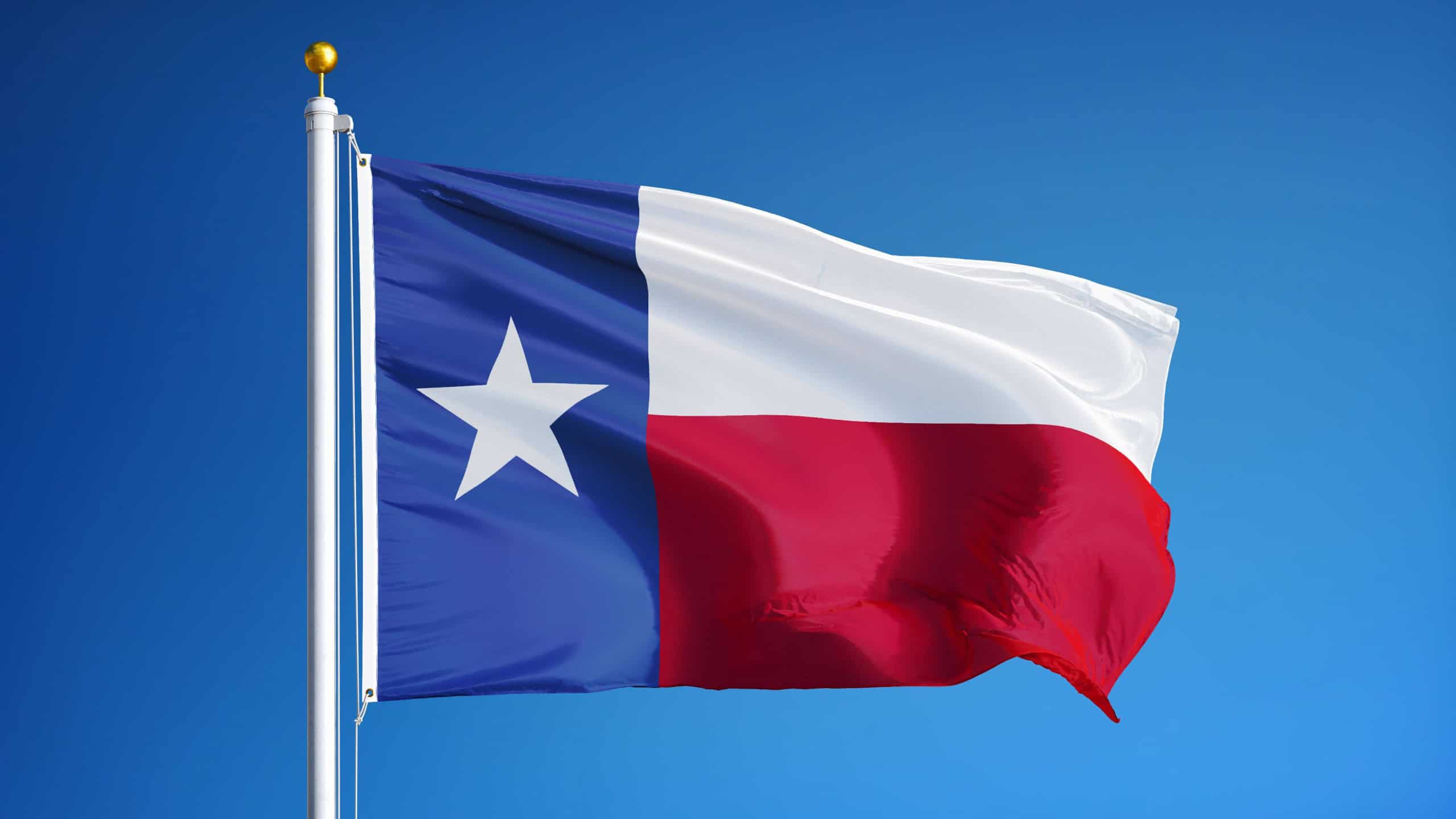 Texas flag waving against clean blue sky, close up