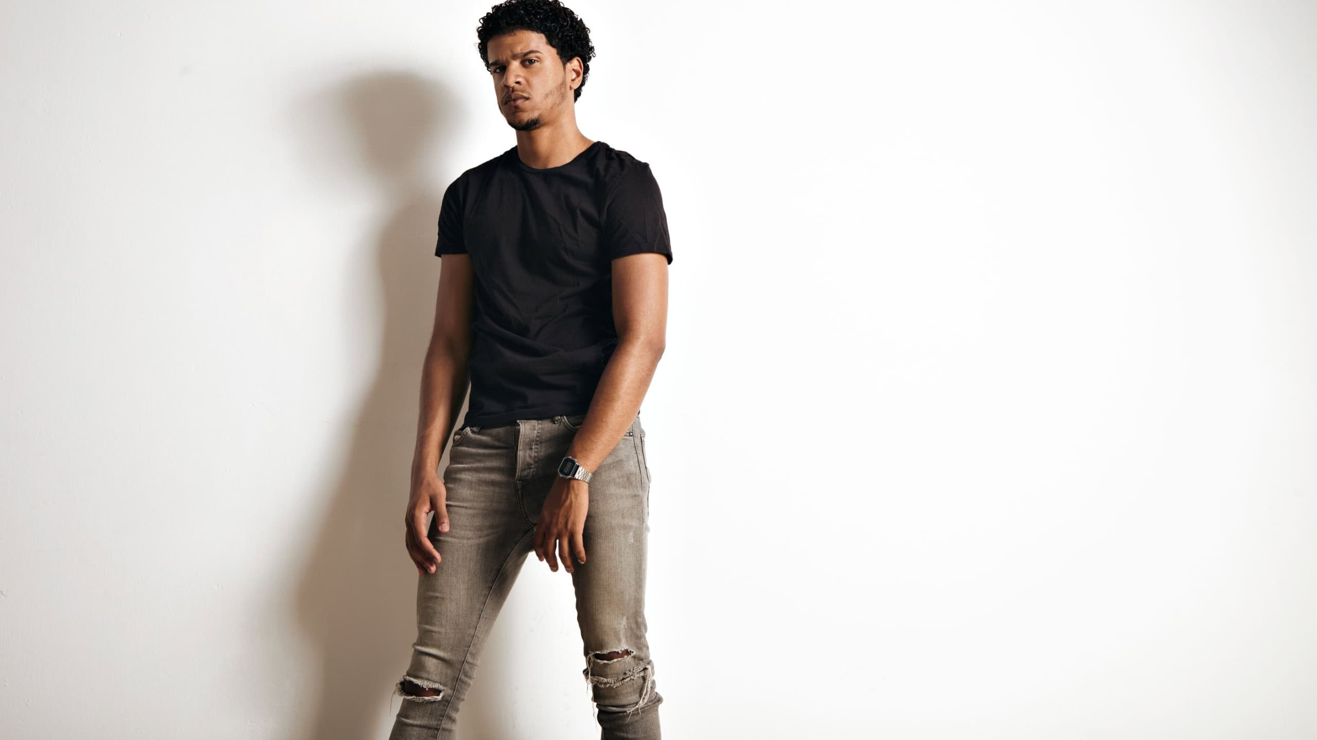 Upset tired muscular black young man in an unlabeled cotton t-shirt and skinny jeans isolated on white