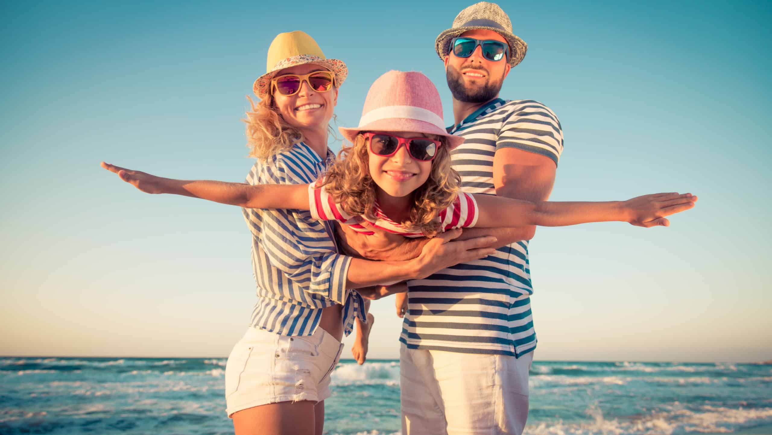 Happy family on the beach. People having fun on summer vacation. Father, mother and child against blue sea and sky background. Holiday travel concept