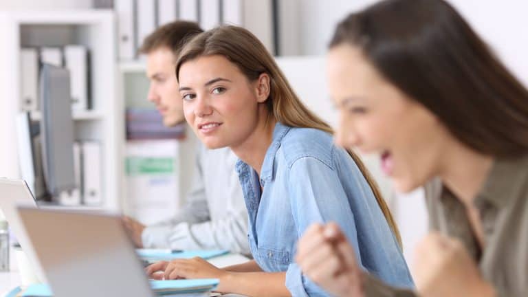 Portrait of a envious employee looking at a successful colleague at office