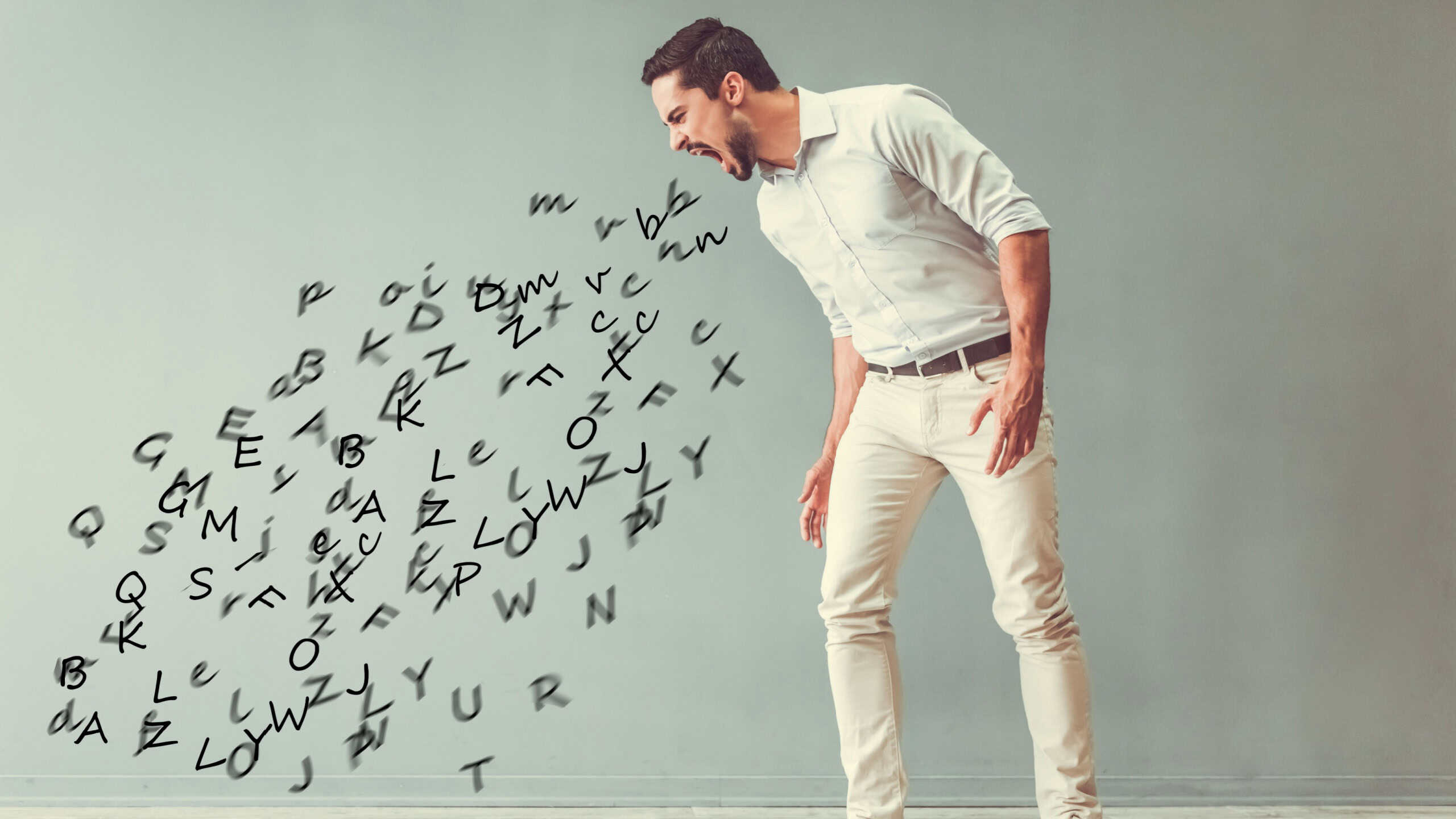 Handsome angry man is yelling and the stream of words going out of his mouth, on gray background