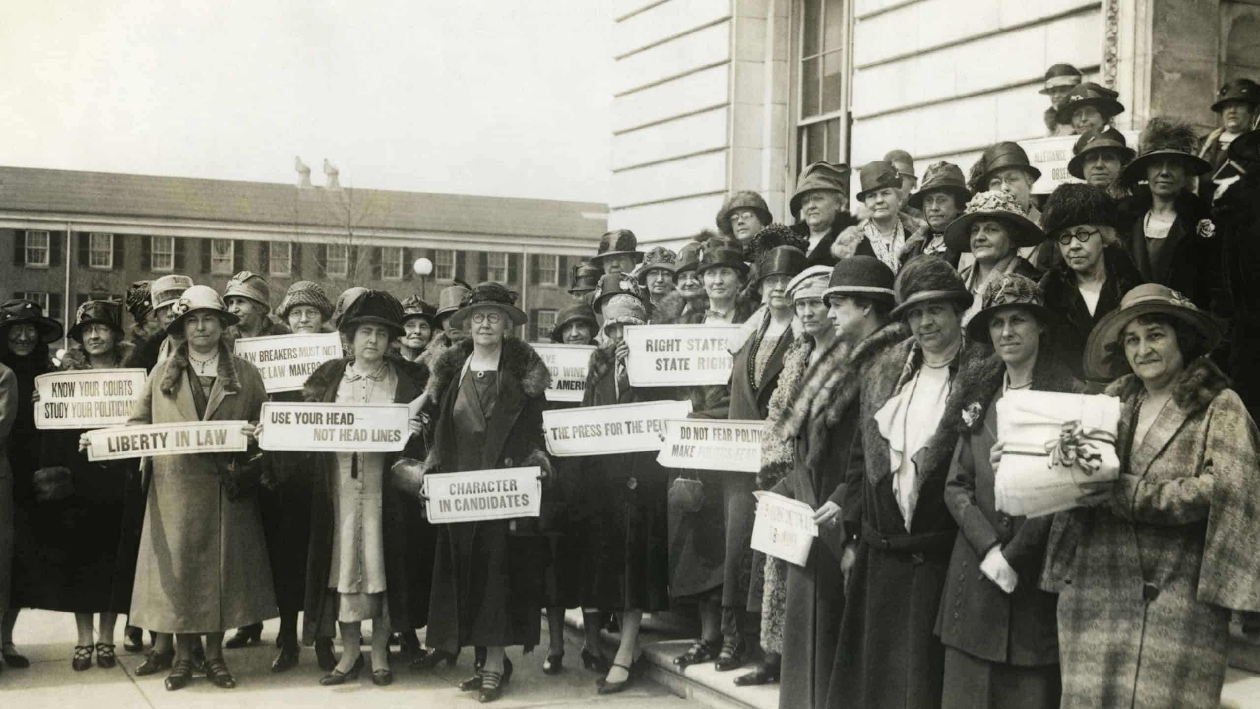 Women Suffragettes holding placards with political activist slogans in 1920. Signs read: Know Your Courts-Study Our Politicians; Liberty in Law; Law Makers Must Not Be Law Breakers; Character in Candi