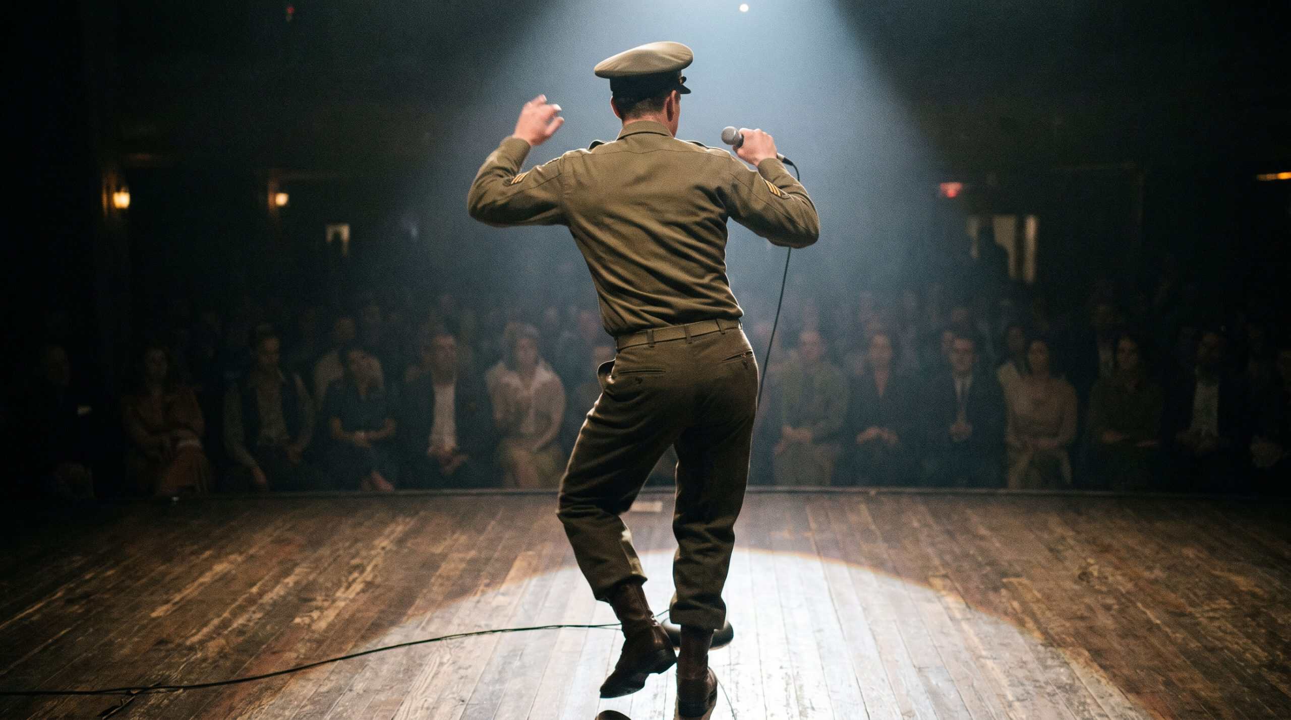 A man who is singing and dancing like Elvis Presley in an army uniform