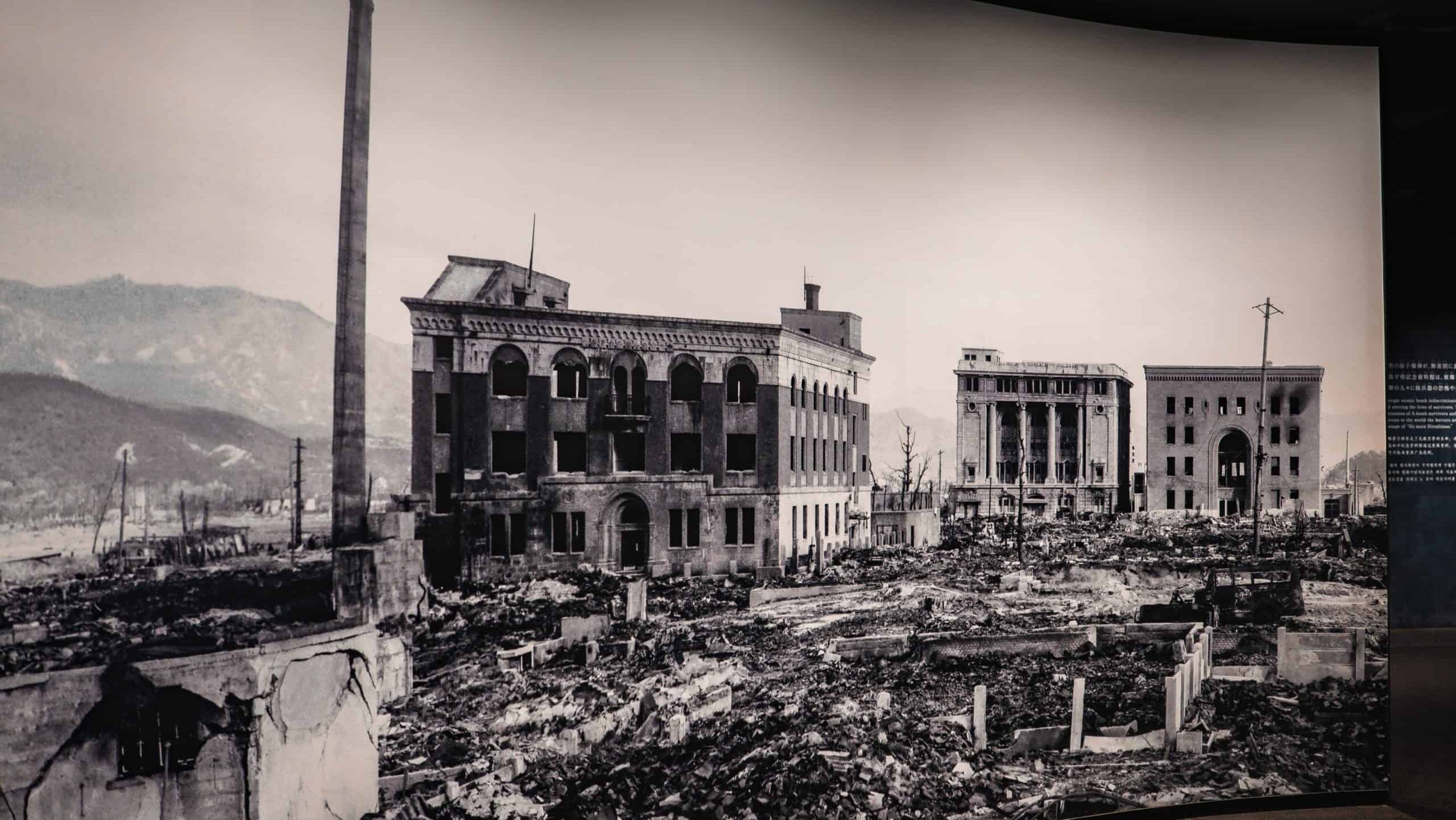 Hiroshima, Japan. May 6, 2025. Black and white view of Hiroshima after the 1945 bombing, gutted masonry blocks, vast rubble, a lone smokestack, distant mountains, museum exhibit context, somber tone