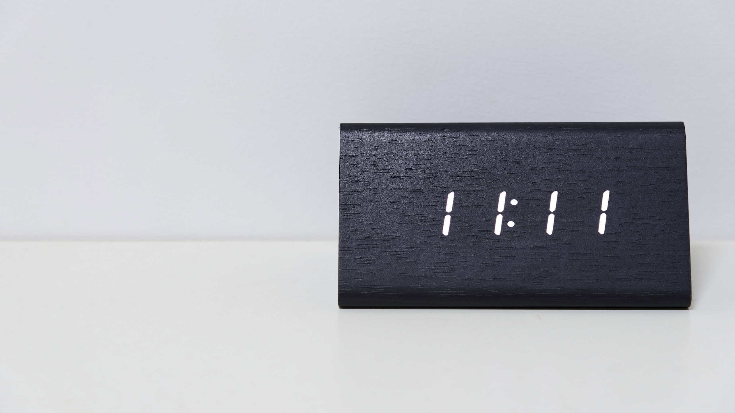Black digital clock on a white background showing time 11:11 (eleven hours eleven minutes)
