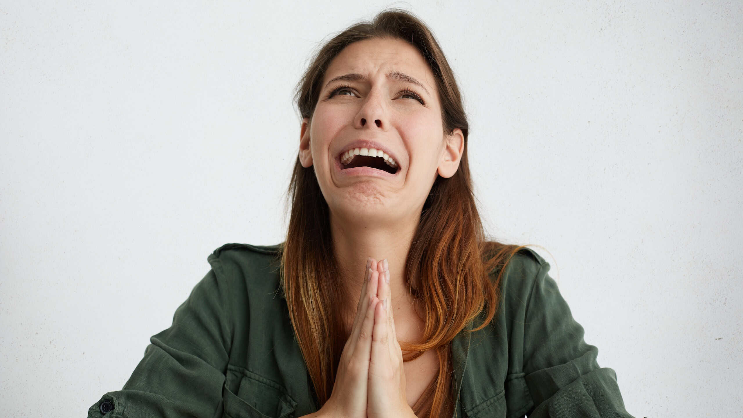 Portrait of desperate woman begging for mercy and crying. Emotional woman holding her palms together looking griveous while begging for something. Crying disappointed female asking for forgiveness