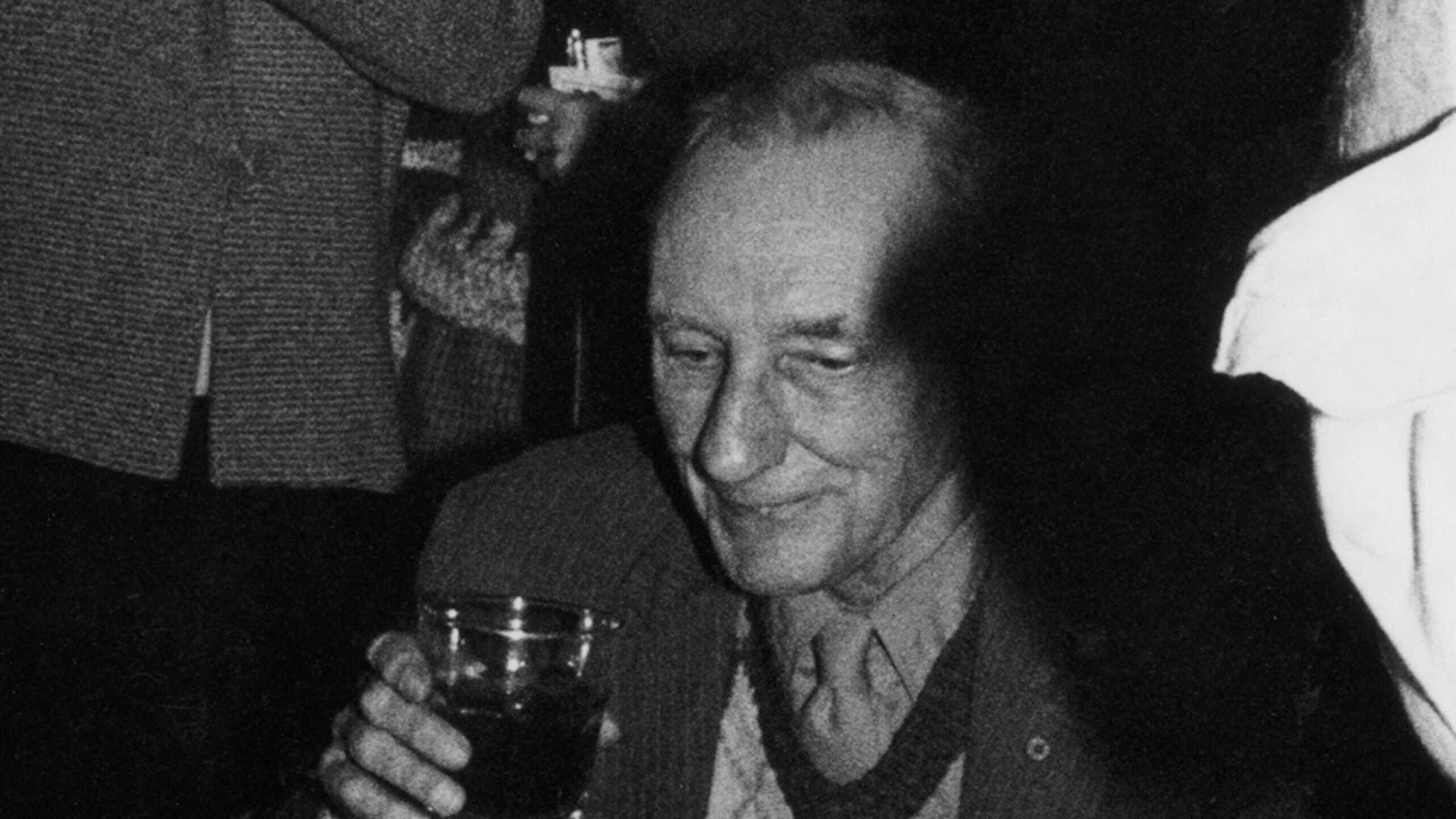 William Burroughs enjoying cake and alcohol at his 70th birthday.