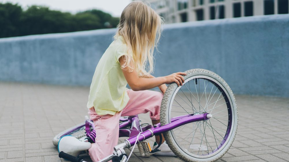 side view of little child fallen from bicycle on road on street