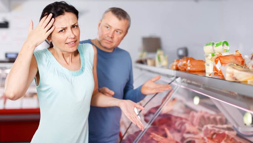 Sad,Couple,Customers,Choosing,Meat,In,Butchers,Shop