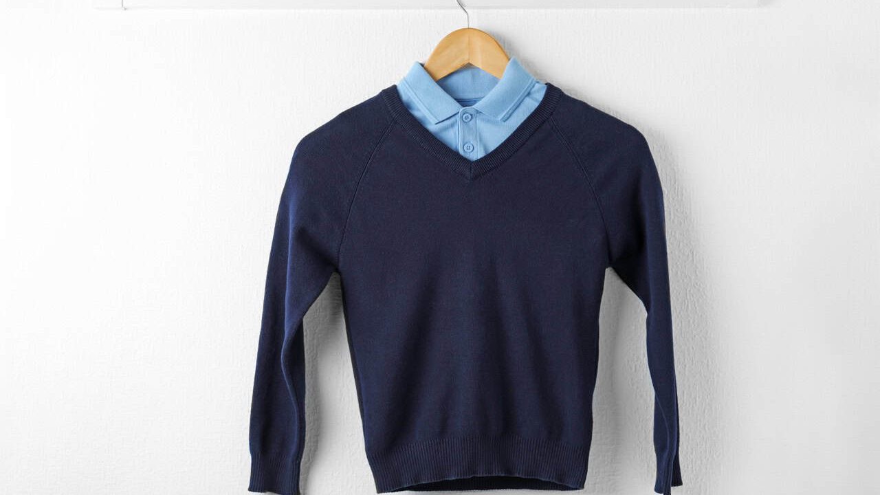 Shirt and jumper on hanger indoors. School uniform