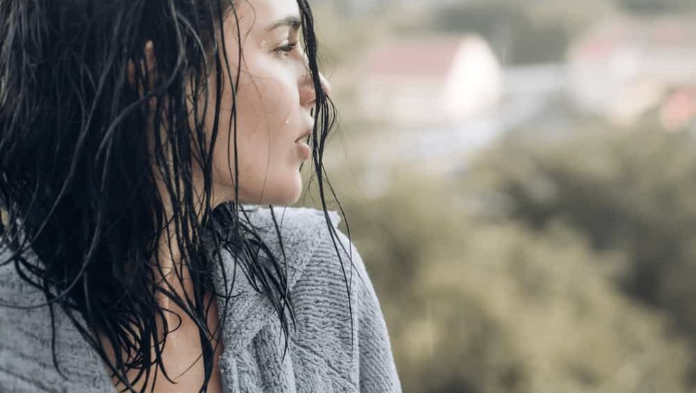 Close-up of young woman with problems crying, looking out