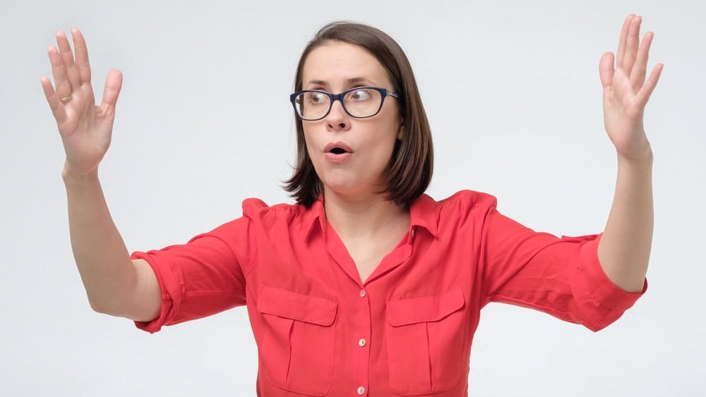 Surprised mature woman in glasses and red clothes making hands the size of big thing. Boast about the size of prize