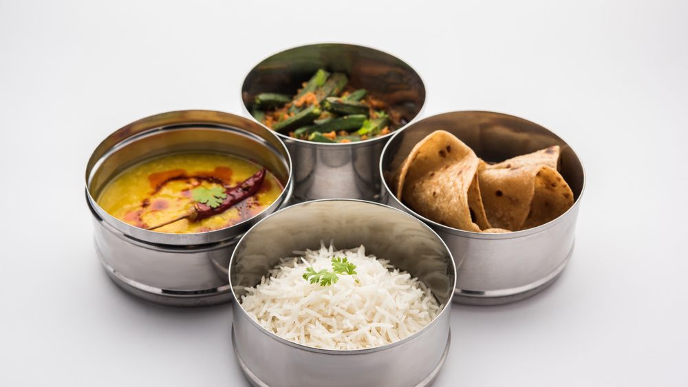 Indian vegetarian Lunch Box or Tiffin made up of stainless steel for office or workplace, includes Dal Fry, Bhindi Masala, Rice with chapati and salad