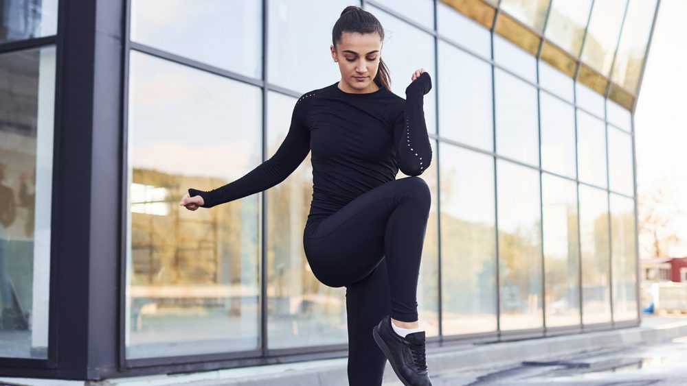 Young brunette in sportive clothes have fitness day outdoors in the city.