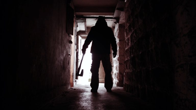Silhouette of Man holding Axe. Hatchet in Arm in dark Hallway. Scary homicide scenes