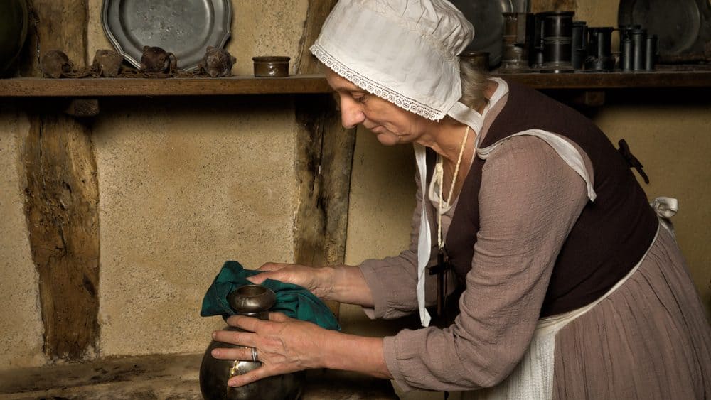 Woman dressed as a medieval peasant maid working in an authentic kitchen in a French castle