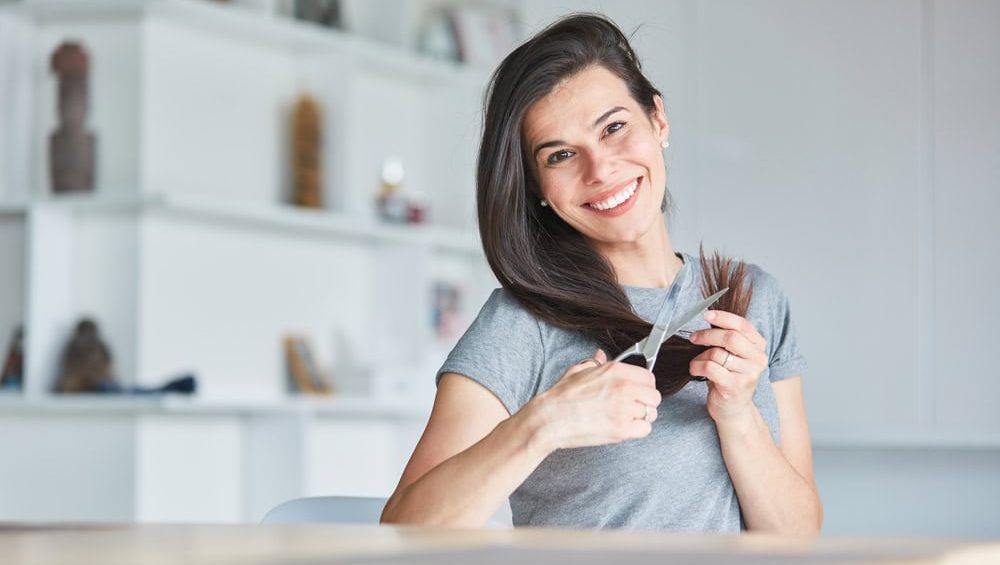 Happy,Young,Woman,Using,Scissors,At,Home,While,Cutting,Her