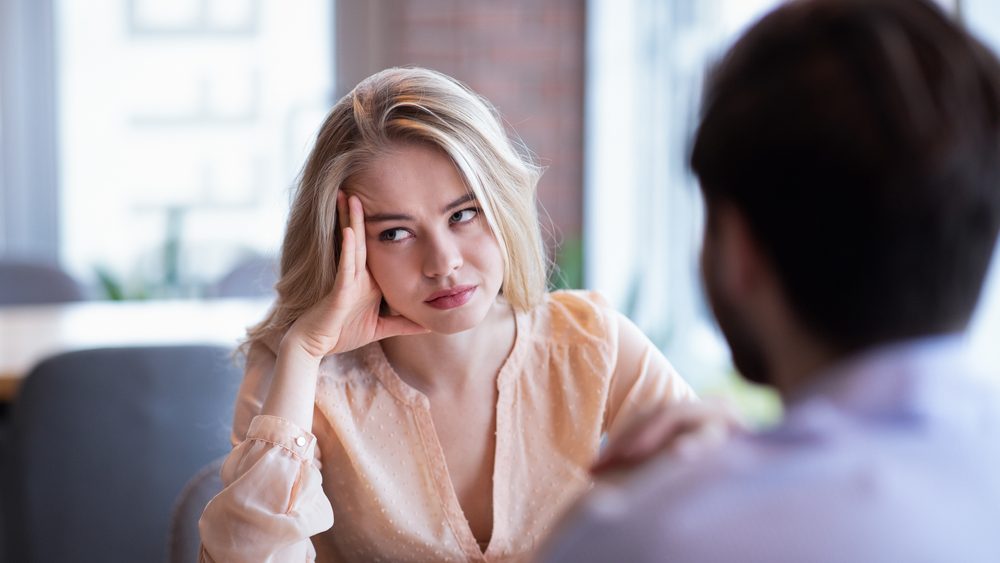 Young Caucasian woman disinterested in blind date, feeling bored with conversation at city cafe. Millennial couple having relationship problems, going through breakup or divorce