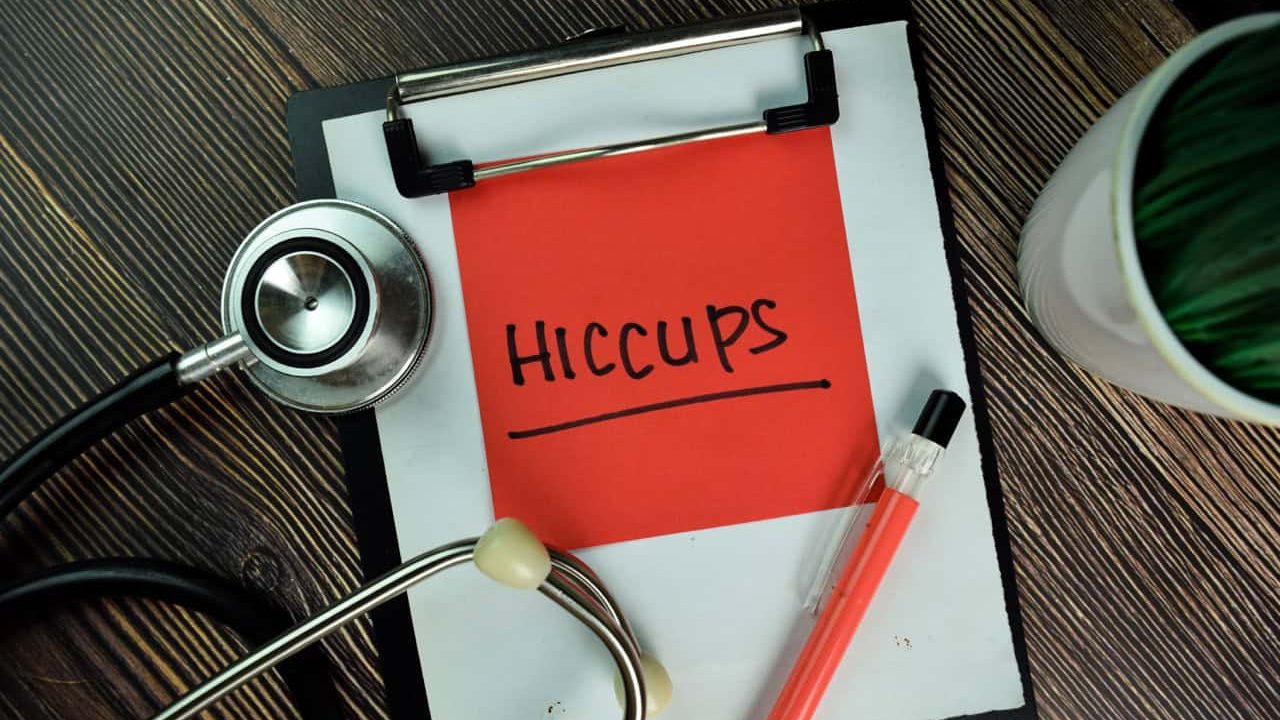 HICCUPS write on sticky notes isolated on Wooden Table.