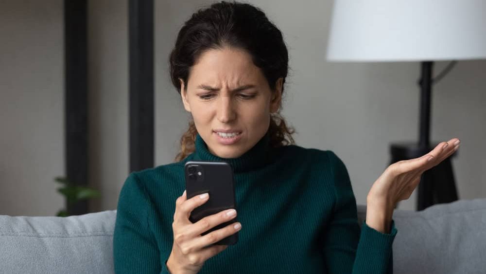 Close up angry dissatisfied woman looking at phone screen, unhappy confused young female having problem with broken smartphone or internet fraud, slow internet connection, reading bad news in message
