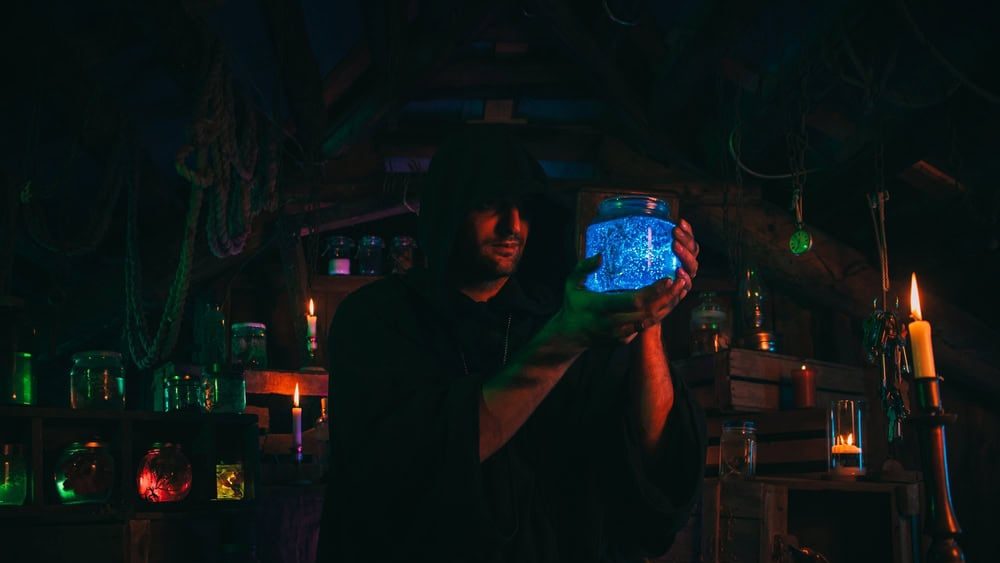 sorcerer alchemist in dark clothes is engaged in potion making in a craft workshop
