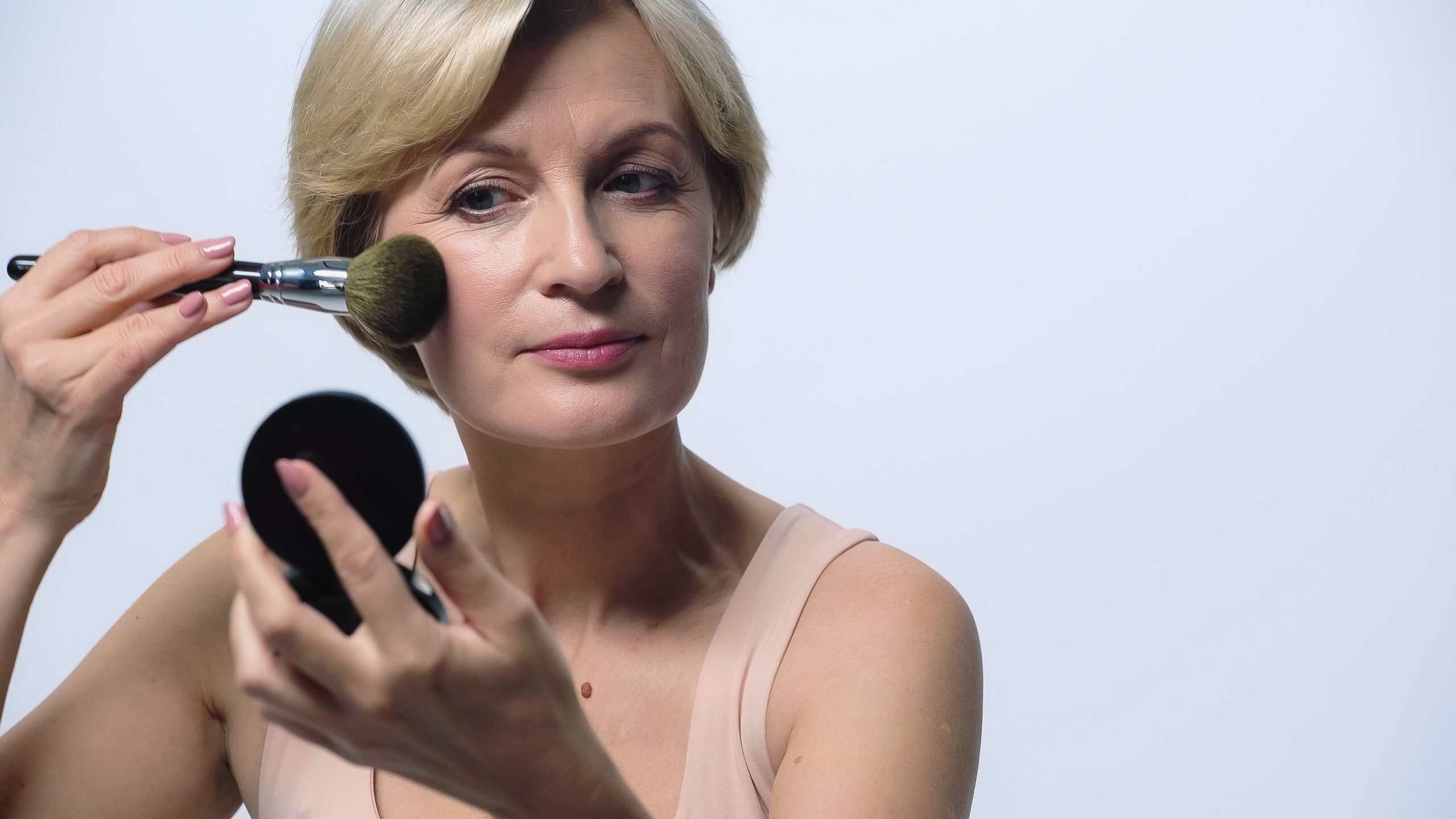 Blonde,Middle,Aged,Woman,Applying,Face,Powder,Isolated,On,White