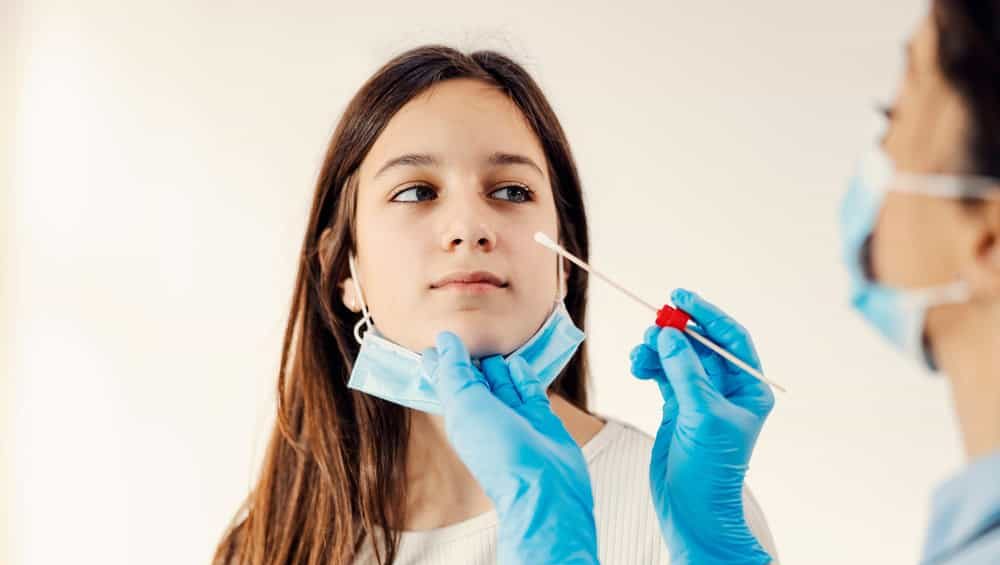 A girl getting tested on covid 19 with PCR test cotton swab. Prevention, medical care and medical service.