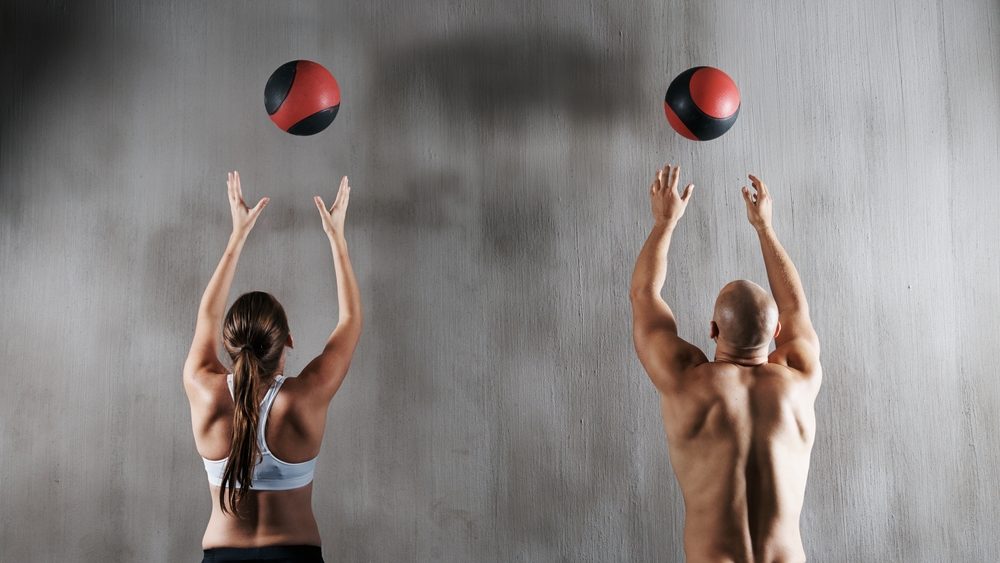 Training to become fighting fit. Shot of a young man and woman working out with medicine balls at the gym.