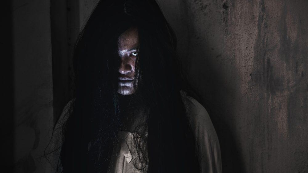 Scary ghost woman. Portrait of Asian ghost or zombie horror creepy scary have hair covering the face her eye at abandoned house dark tone, female make up zombie face, Happy Halloween day concept